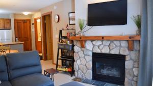 Fireside Lodge #215 by Bear Country في صن بيكس: غرفة معيشة مع موقد وتلفزيون بشاشة مسطحة فوقها