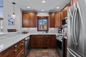 a kitchen with wooden cabinets and a stainless steel refrigerator at Trappers Landing #05 By Bear Country in Sun Peaks