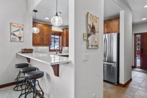 a kitchen with a counter and a refrigerator and stools at Trappers Landing #05 By Bear Country in Sun Peaks