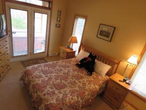 a black cat sitting on a bed in a bedroom at Crystal Forest #63 By Bear Country in Sun Peaks