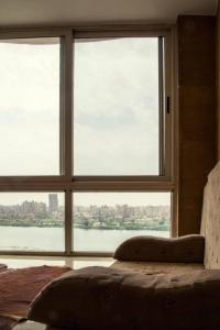 Dormitorio con ventana grande con vistas al agua en LuxuryApartmentDirectToTheNile en El Cairo