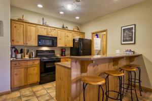 a kitchen with wooden cabinets and a bar with stools at Crystal Forest #65 By Bear Country in Sun Peaks