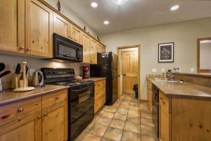 a kitchen with wooden cabinets and a black refrigerator at Crystal Forest #65 By Bear Country in Sun Peaks
