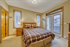a bedroom with a bed and two windows at Crystal Forest #65 By Bear Country in Sun Peaks