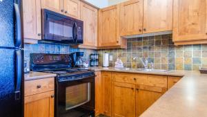 a kitchen with wooden cabinets and a black stove top oven at Settlers Crossing #61 by Bear Country in Sun Peaks