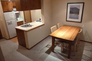 a kitchen with a wooden table and a kitchen with a sink at Fireside Lodge #223 By Bear Country in Sun Peaks