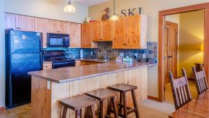 uma cozinha com armários de madeira e um frigorífico preto em Settlers Crossing #11 by Bear Country em Sun Peaks