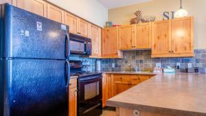 La cuisine est équipée d'un réfrigérateur bleu et de placards en bois. dans l'établissement Settlers Crossing #11 by Bear Country, à Sun Peaks