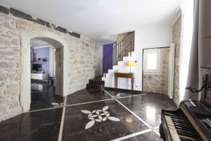 a living room with a stone wall and a piano at Casa Hybla in Ragusa