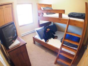 a room with three bunk beds and a television at Crystal Forest #60 By Bear Country in Sun Peaks