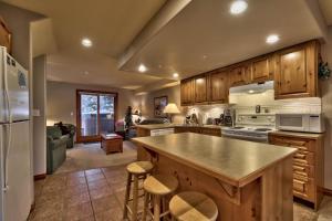 a kitchen with wooden cabinets and a kitchen island with stools at Timberline Village #14 By Bear Country in Sun Peaks