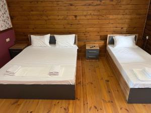 two beds in a room with wooden walls and wooden floors at Olympia in Gudauta