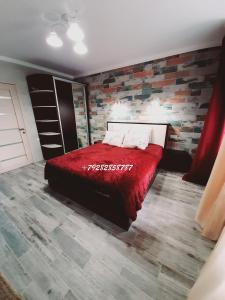 ピャチゴルスクにあるNiNA - трехкомнатная квартираの赤いベッドとレンガの壁が備わるベッドルーム1室が備わります。