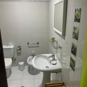 a white bathroom with a sink and a toilet at Sea to see - sea front view in Caniço