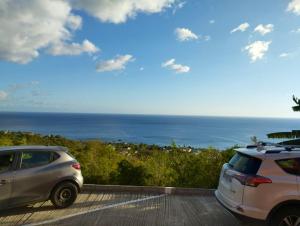 two cars parked in a parking lot near the ocean at Appartement d'une chambre avec vue sur la mer terrasse amenagee et wifi a Bouillante a 4 km de la plage in Bouillante