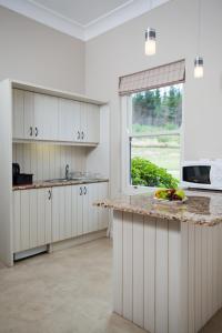 uma cozinha com armários brancos e uma grande janela em Gaikou Lodge em Swellendam