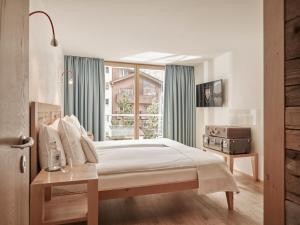 a bedroom with a bed and a window at Firefly Luxury Suites in Zermatt