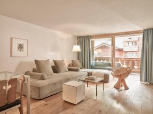 a living room with a couch and a large window at Firefly Luxury Suites in Zermatt