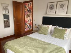 a bedroom with a large bed with two green pillows at A Casa do Correo Vello - O Balcón in Pontevedra
