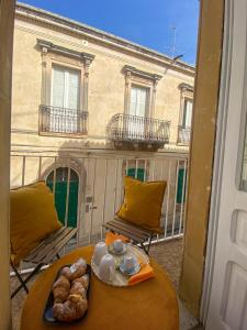 a table with a plate of food on a balcony at Casa Noto in Noto