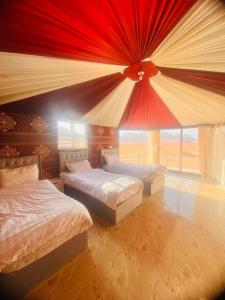 Desert guide camp في وادي رم: غرفة نوم بسريرين ونافذة كبيرة