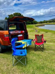 duas cadeiras sentadas na frente de um carro e uma mesa em Campervan/Maui hosted by Go Camp Maui em Kihei