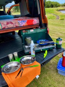 an open back compartment of a vehicle with plates and pans at Campervan/Maui hosted by Go Camp Maui in Kihei
