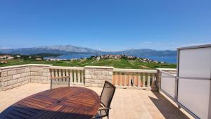 a balcony with a wooden table and a view of the water at VILLA Apartments Mate Cebalo in Lumbarda