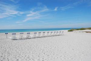 una fila de sillas sentadas en una playa blanca en Gulf Tides of Longboat Key, en Longboat Key