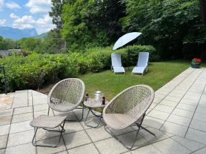 2 Stühle und ein Tisch mit Sonnenschirm auf der Terrasse in der Unterkunft Die Landhausvilla in Unterach am Attersee in Unterach am Attersee