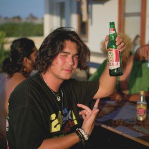 un joven sosteniendo una botella de cerveza en Sunshot Hostel en Legian