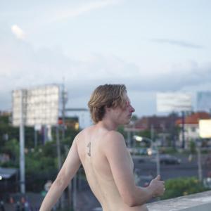 Ein Mann ohne Hemd mit einer Tätowierung auf der Schulter. in der Unterkunft Sunshot Hostel in Legian