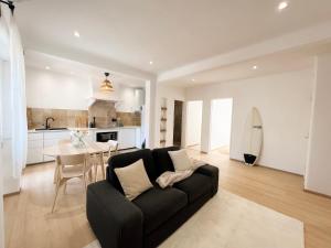 a living room with a black couch and a table at Capitão Ribeiro Surf House in Costa da Caparica