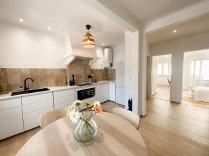 a kitchen with a table with a vase of flowers on it at Capitão Ribeiro Surf House in Costa da Caparica +12 photos