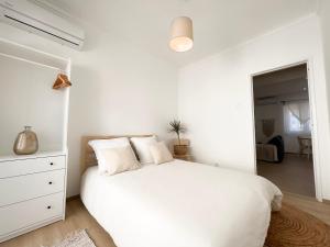 a white bedroom with a white bed and a dresser at Capitão Ribeiro Surf House in Costa da Caparica