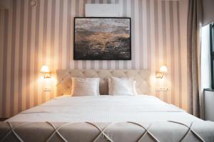 een slaapkamer met een groot wit bed met 2 lampen bij La Forteresse in Borgloon