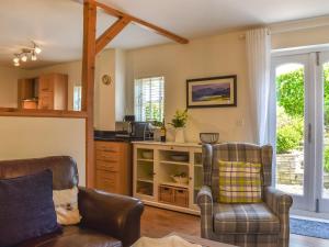 a living room with two chairs and a kitchen at Cosy Cottage in Holker