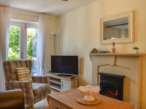a living room with a television and a fireplace at Cosy Cottage in Holker
