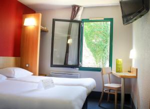 Habitación de hotel con 2 camas y ventana en Hotel Inn design Vierzon - ex B&B en Vierzon