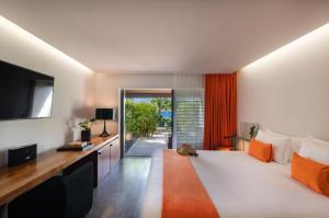 Schlafzimmer mit einem großen Bett, einem Schreibtisch und einem TV in der Unterkunft Hotel Christopher Saint Barth in Gustavia