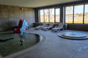 a room with a swimming pool with chairs and a table at Wakacyjny apartament & SPA nad morzem in Dziwnów