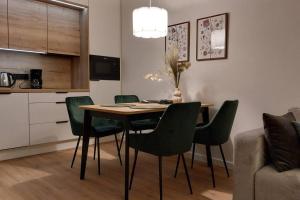 a dining room table with green chairs in a kitchen at Wakacyjny apartament & SPA nad morzem in Dziwnów