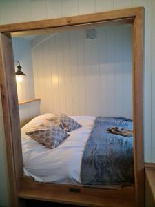 uma cama num quadro com duas almofadas em Milberry Green Meadows em Warlingham