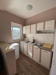 a small kitchen with white cabinets and a window at Apartments Klikovac Liman II in Ulcinj