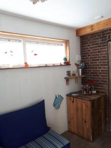 Habitación con cama, ventana y pared de ladrillo. en Tiny home Texel, en Den Burg