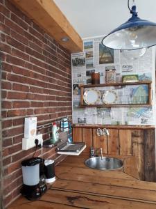 a kitchen with a sink and a brick wall at Tiny home Texel in Den Burg