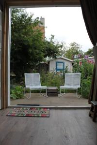 2 sillas blancas sentadas en un porche con espejo en Tiny home Texel, en Den Burg