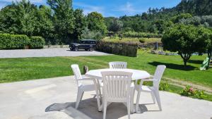a white table and chairs with a car in the background at Quinta do Paúl de Baixo in Guimarães