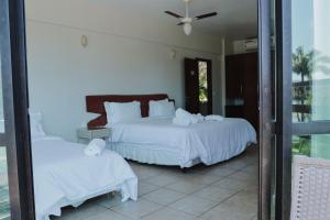 een slaapkamer met 2 bedden en witte lakens bij Hotel Lago do Sol in Itaúna
