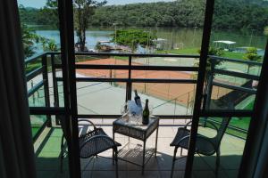 een balkon met 2 stoelen en een tafel met wijnflessen bij Hotel Lago do Sol in Itaúna